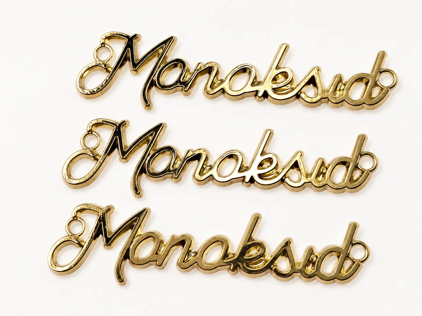 Gold script style metal logo charms on a white background